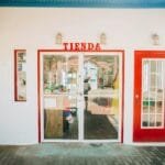 Charming storefront with red doors and glass entry, featuring TIENDA sign.