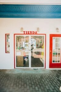 Charming storefront with red doors and glass entry, featuring TIENDA sign.