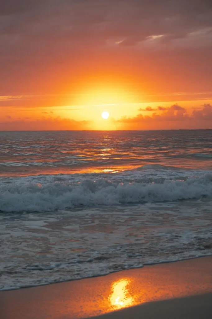 Captivating sunset at Punta Cana, Dominican Republic, with waves gently lapping the sandy shore.